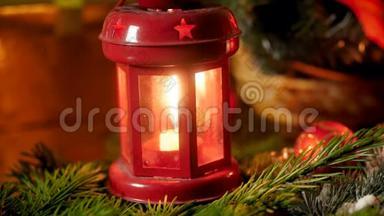 在圣诞树树枝上用燃烧的蜡烛拍摄红色灯笼的特写镜头。 冬天的完美背景
